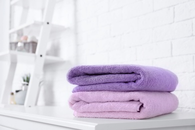 Stack of fresh towels on table in bathroom. Space for text