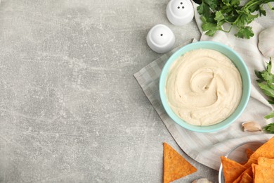 Delicious hummus, nachos and parsley on grey table, flat lay. Space for text