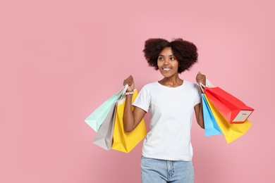 Photo of Happy African American woman with shopping bags on pink background. Space for text
