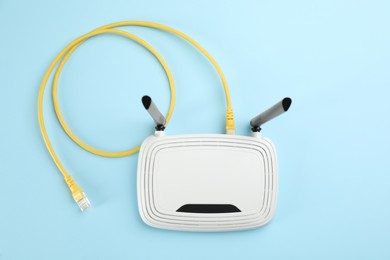 Photo of Modern Wi-Fi router on light blue background, top view