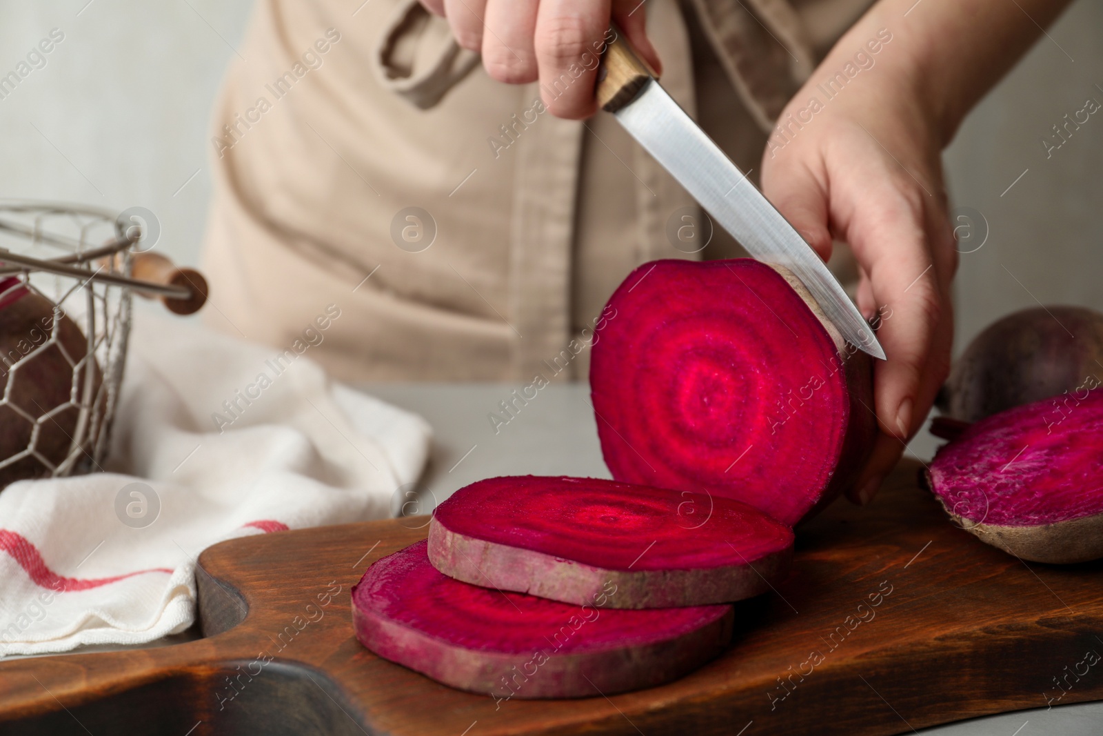 Photo of Woman cutting fresh red beet at table, closeup