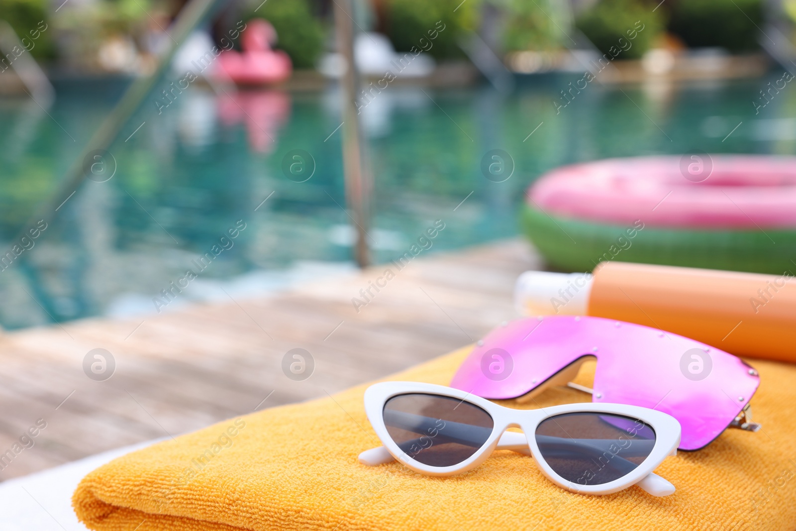 Photo of Beach towels and sunglasses on sun lounger near outdoor swimming pool at luxury resort, closeup. Space for text