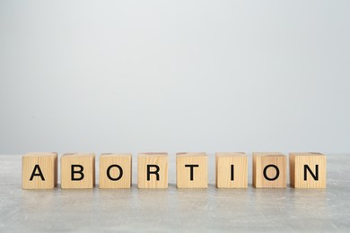 Photo of Word Abortion made of wooden cubes on grey table