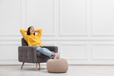 Photo of Beautiful woman relaxing in armchair near white wall indoors, space for text