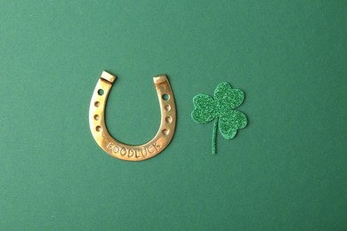St. Patrick's day. Golden horseshoe and decorative clover leaf on green background, flat lay