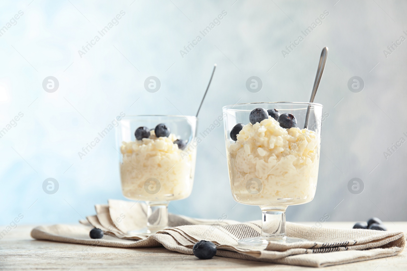 Photo of Creamy rice pudding with blueberries in dessert bowls on table. Space for text