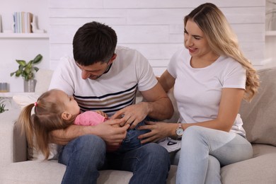 Family with little daughter spending time together on sofa at home