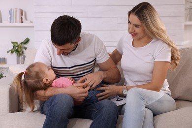 Photo of Family with little daughter spending time together on sofa at home