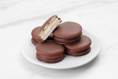 Saucer with delicious choco pies on white table