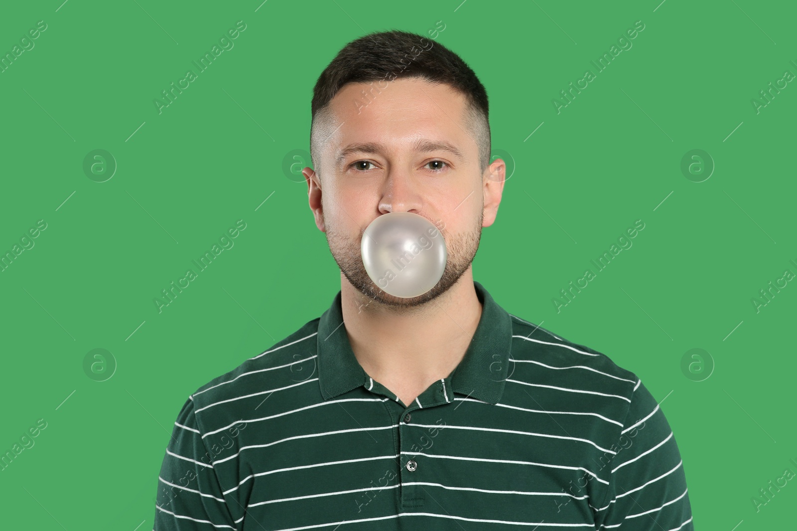 Photo of Handsome man blowing bubble gum on green background