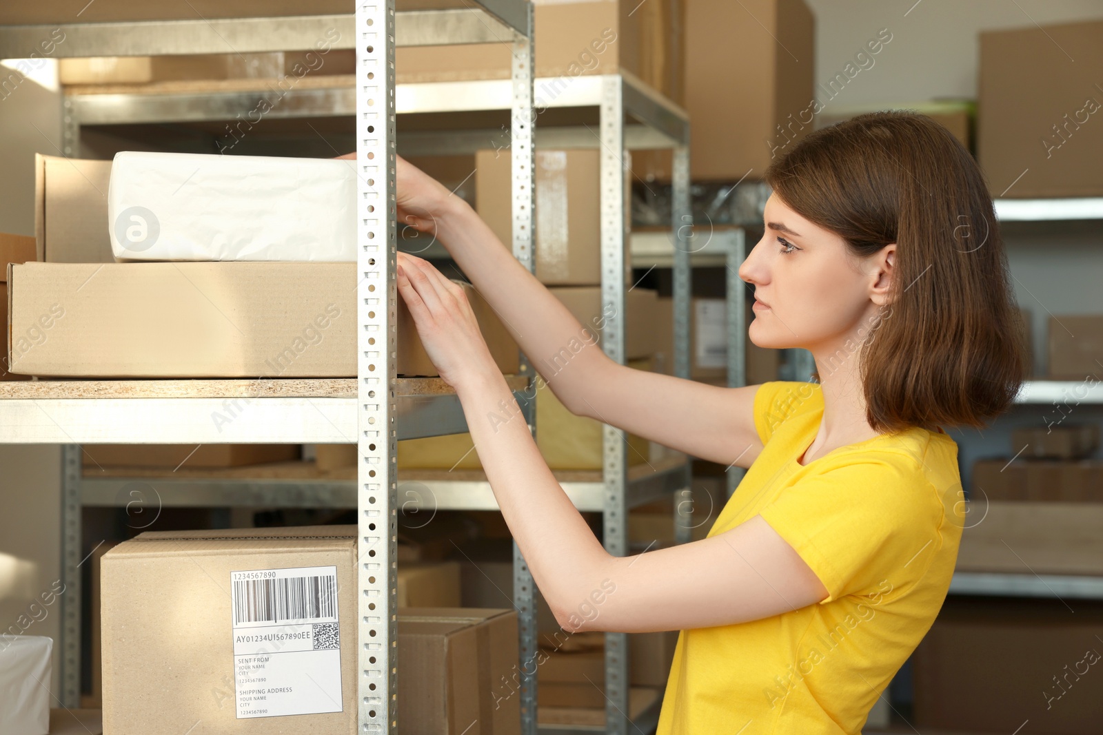 Photo of Post office worker taking parcel from rack indoors