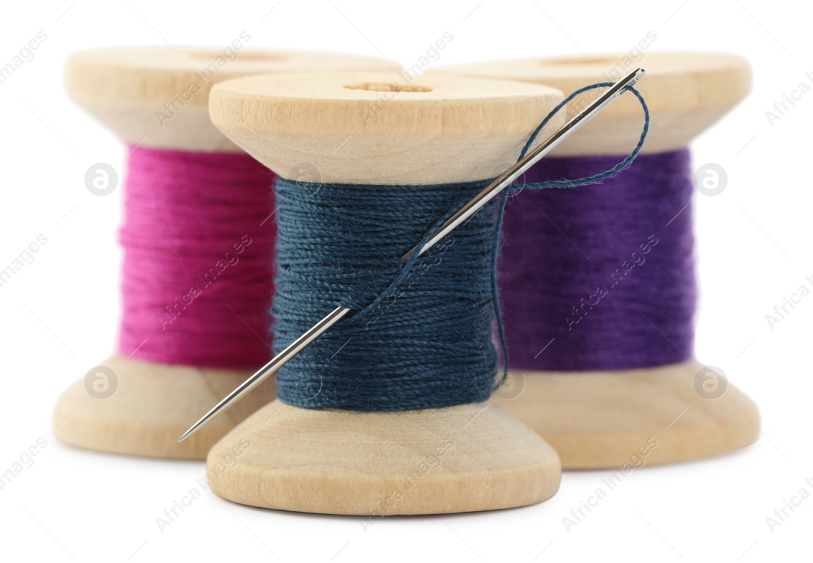 Photo of Different colorful sewing threads with needle on white background, closeup