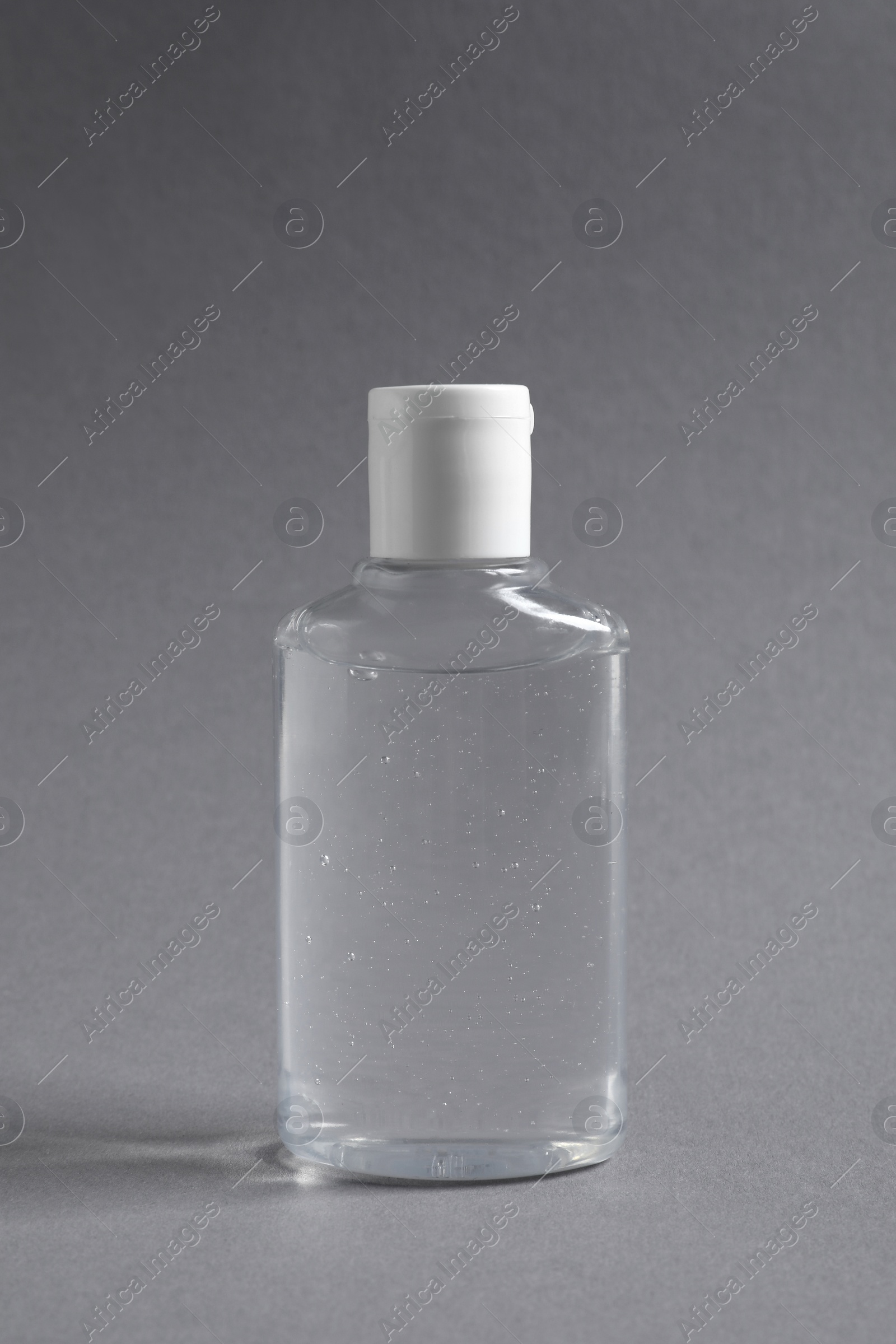 Photo of Transparent bottle with cosmetic product on grey background