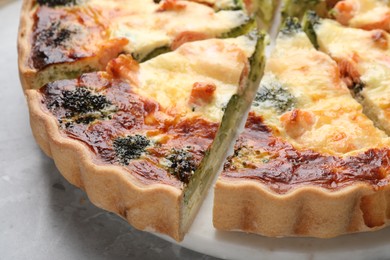 Photo of Delicious homemade quiche and ingredients on light gray table, closeup