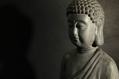 Photo of Buddha statue on dark background, closeup. Space for text