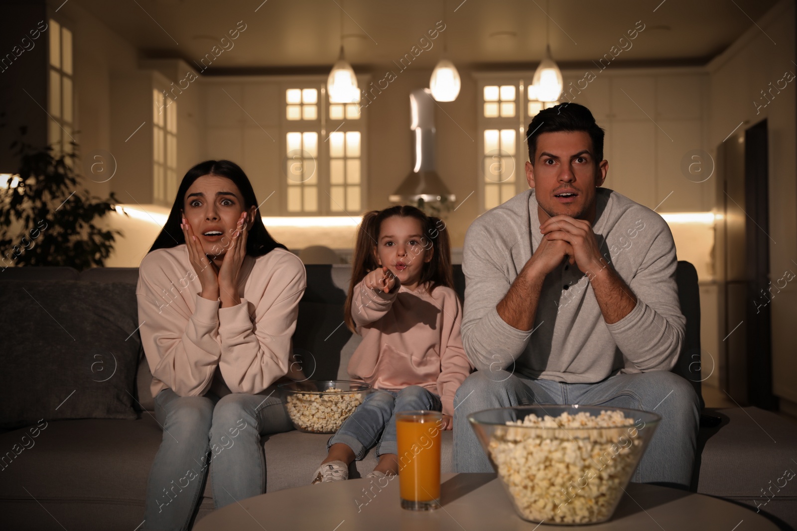 Photo of Family watching movie with popcorn on sofa at night