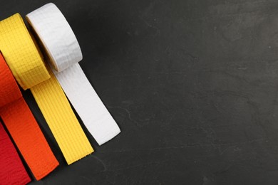 Colorful karate belts on gray background, flat lay. Space for text