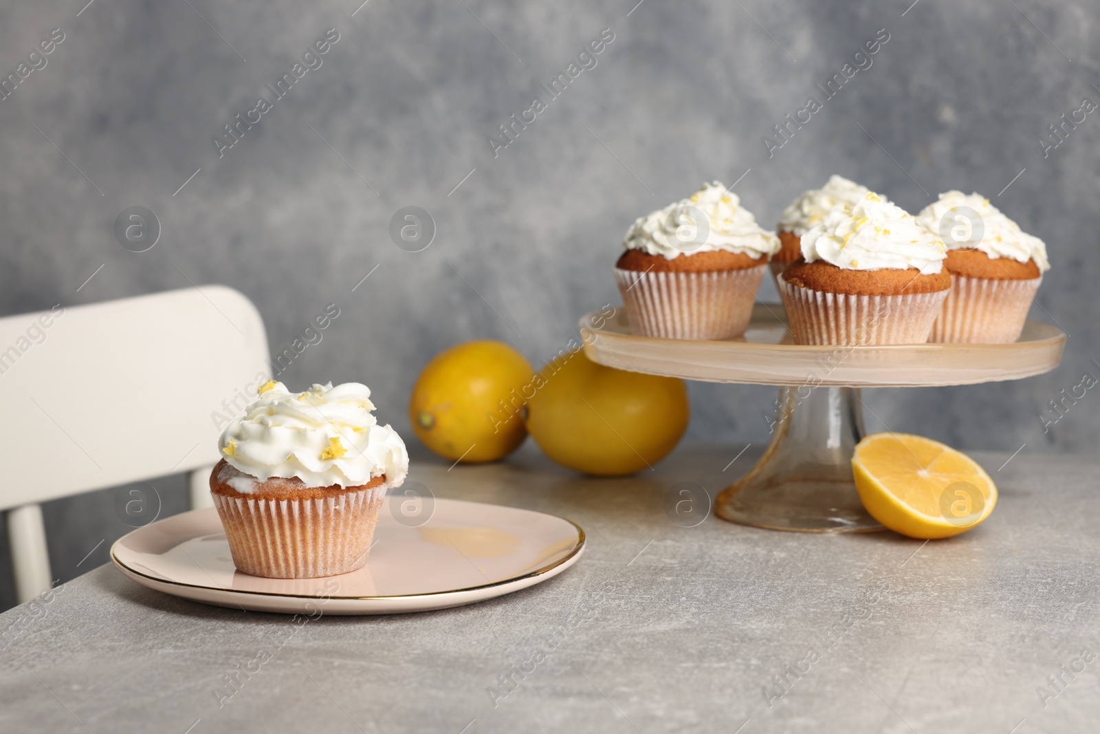 Photo of Delicious cupcakes with cream and lemon zest on gray table