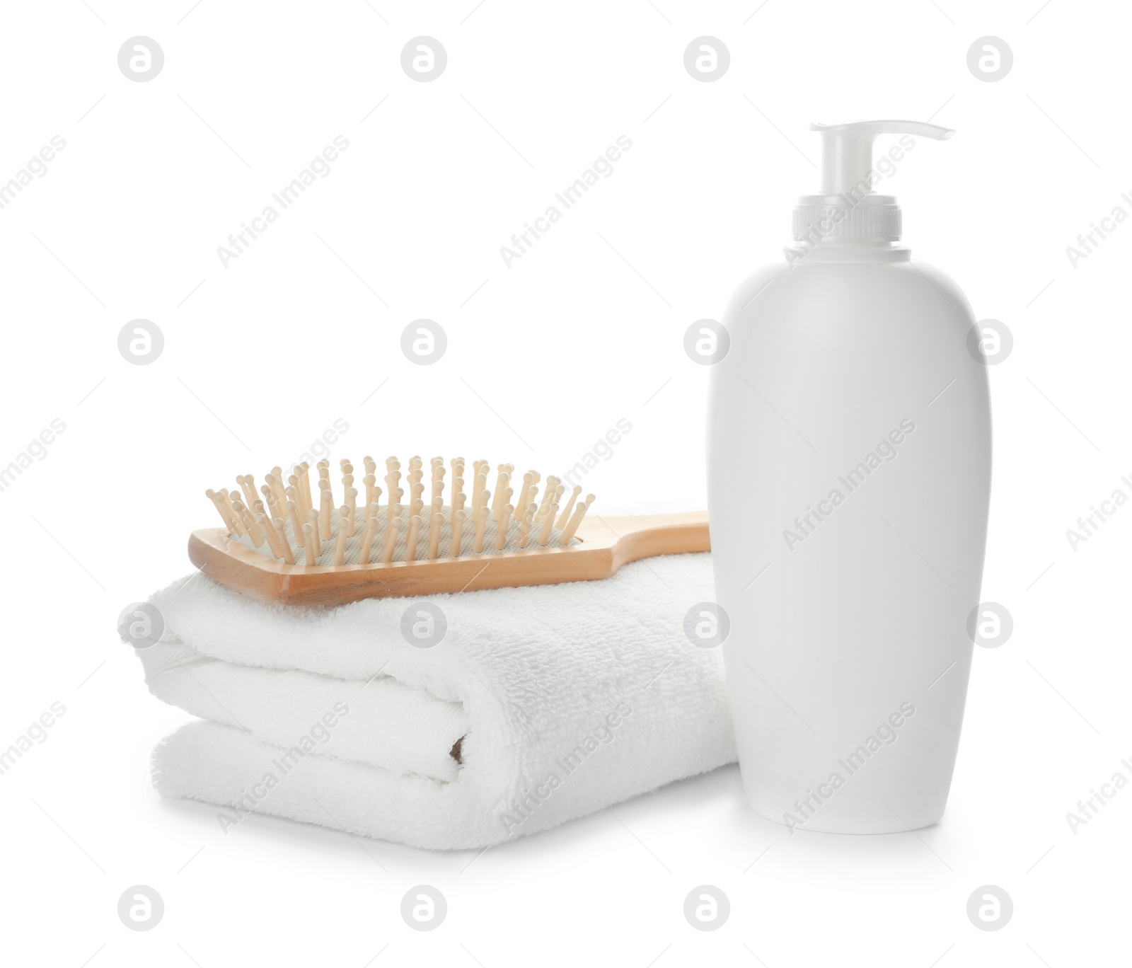 Photo of Folded towel, hair brush and shampoo isolated on white