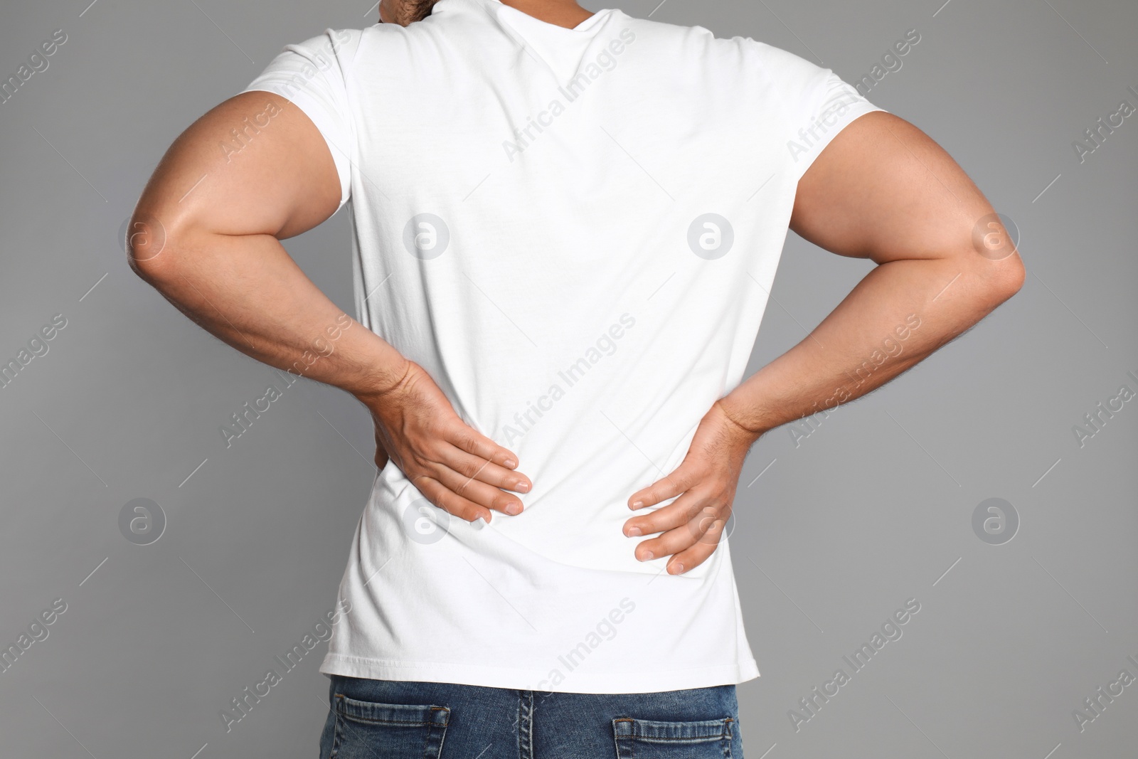 Photo of Man suffering from backache on light grey background, closeup