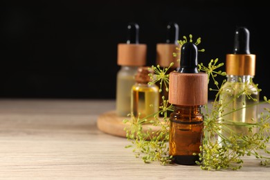 Photo of Bottles of essential oil and fresh dill on wooden table. Space for text