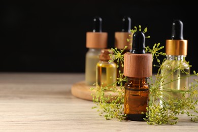 Bottles of essential oil and fresh dill on wooden table. Space for text