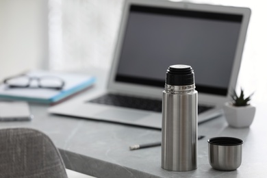 Photo of Thermo bottle on table in modern office