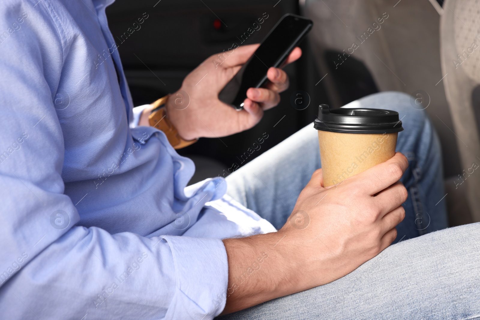 Photo of Coffee to go. Man with paper cup of drink and smartphone in car, closeup