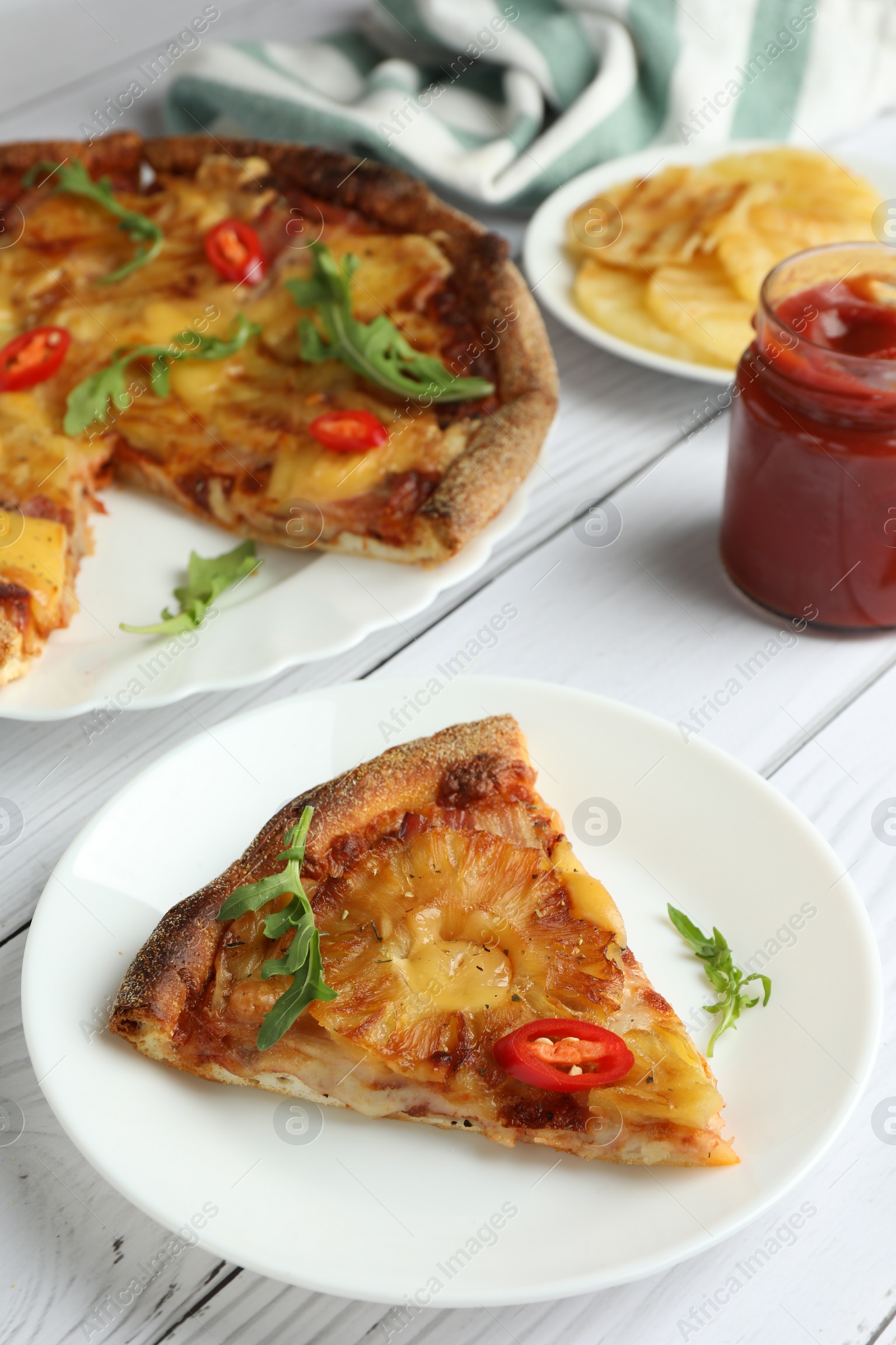 Photo of Plate with piece of delicious pineapple pizza on white wooden table