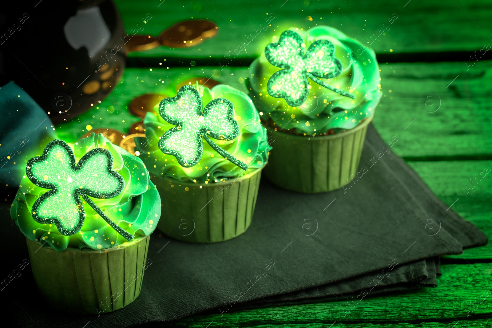 Image of St. Patrick's day. Tasty cupcakes with clover leaf toppers and cream on green wooden table, closeup