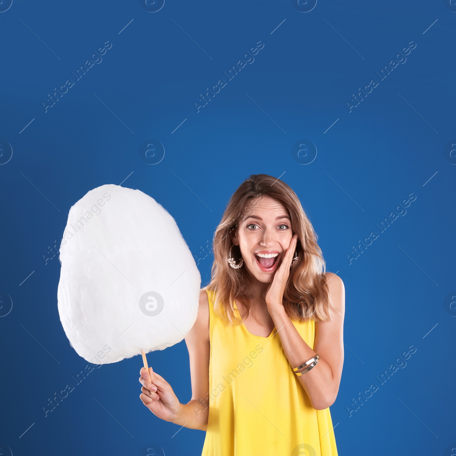 Photo of Emotional woman with cotton candy on blue background