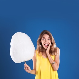 Photo of Emotional woman with cotton candy on blue background