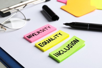 Photo of Sticky notes with words Diversity, Equality, Inclusion and marker on clipboard, closeup