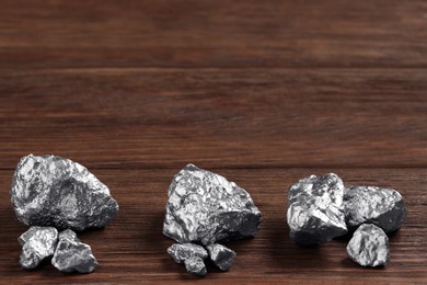 Photo of Many silver nuggets on wooden table. Space for text