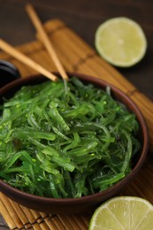 Photo of Tasty seaweed salad in bowl served on table, closeup