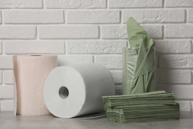Photo of Different paper towels and napkins on grey table near white brick wall