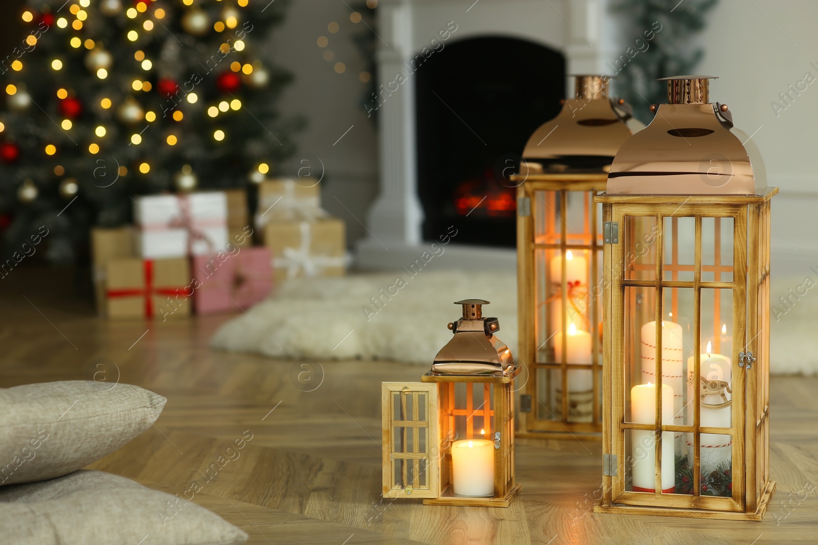 Photo of Christmas lanterns with burning candles in decorated living room. Space for text