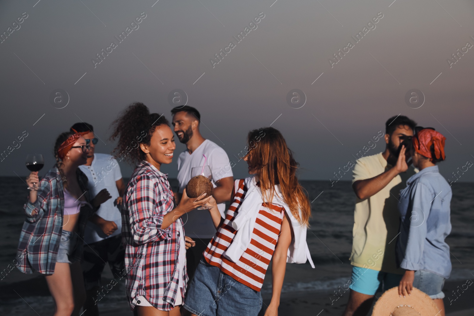 Photo of Happy friends enjoying summer beach party in evening