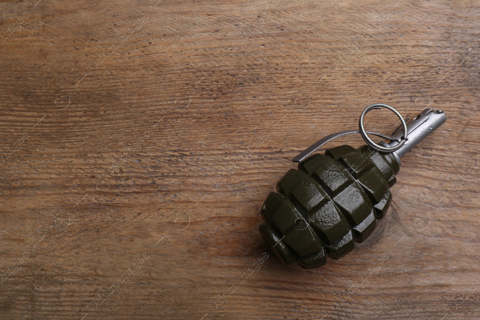 Photo of Hand grenade on wooden table, top view. Space for text