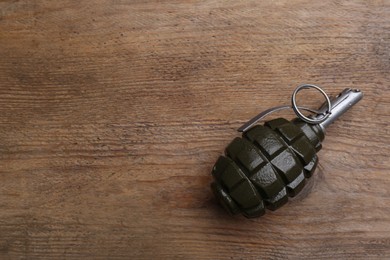 Photo of Hand grenade on wooden table, top view. Space for text