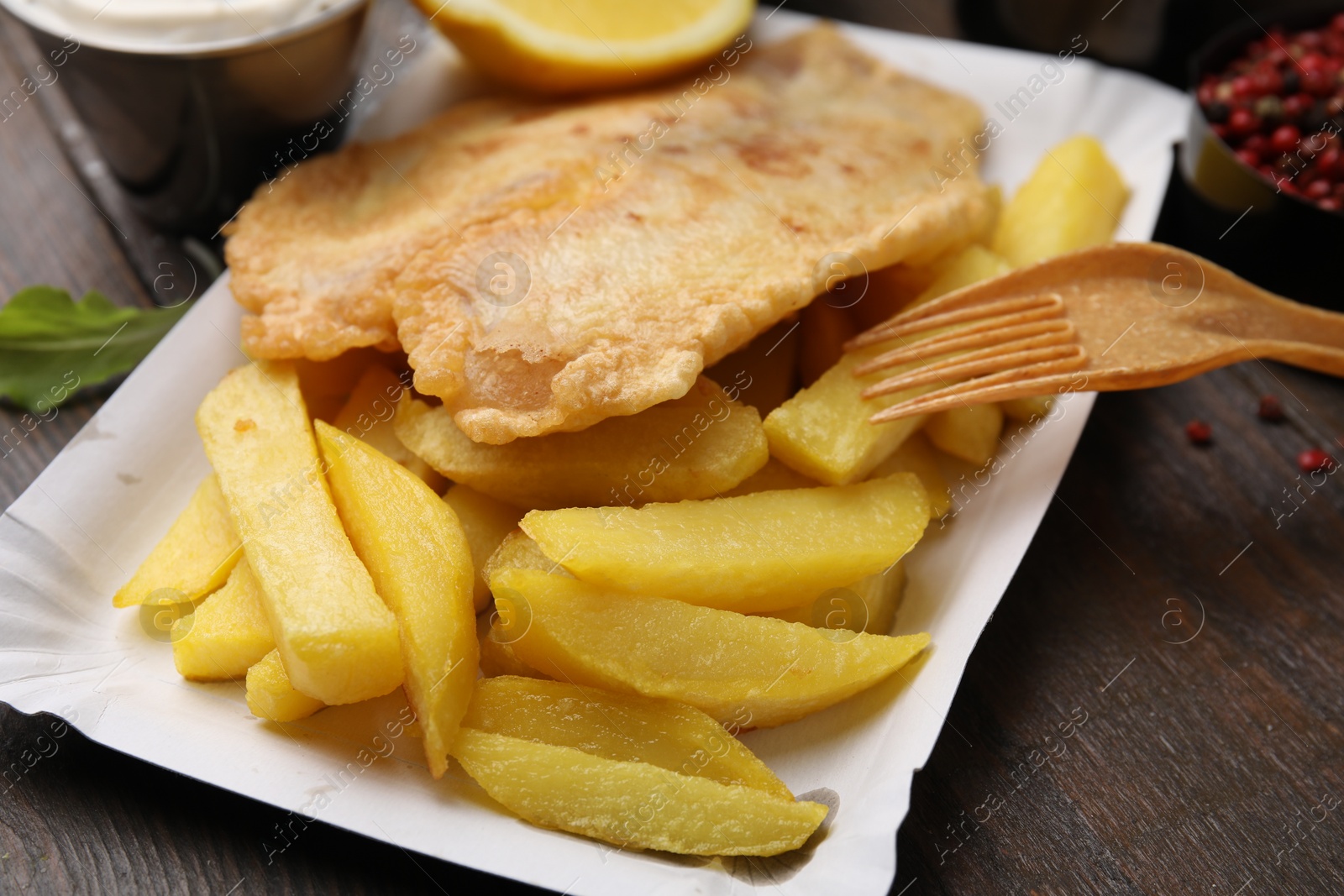 Photo of Delicious fish and chips served on wooden table, closeup