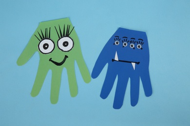 Photo of Funny hand shaped monsters on light blue background, flat lay. Halloween decoration