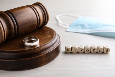 Cubes with word Divorce, wedding ring, gavel and protective mask on white wooden table