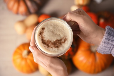 Photo of Woman holding glass cup with pumpkin spice latte, top view