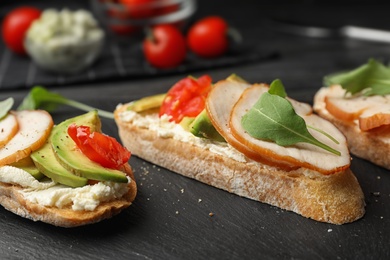 Slate plate of delicious chicken bruschettas on table, closeup