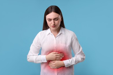 Image of Woman suffering from stomach pain on light blue background