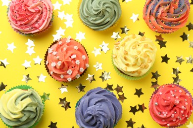 Photo of Delicious cupcake with bright cream and shiny confetti on yellow background, flat lay