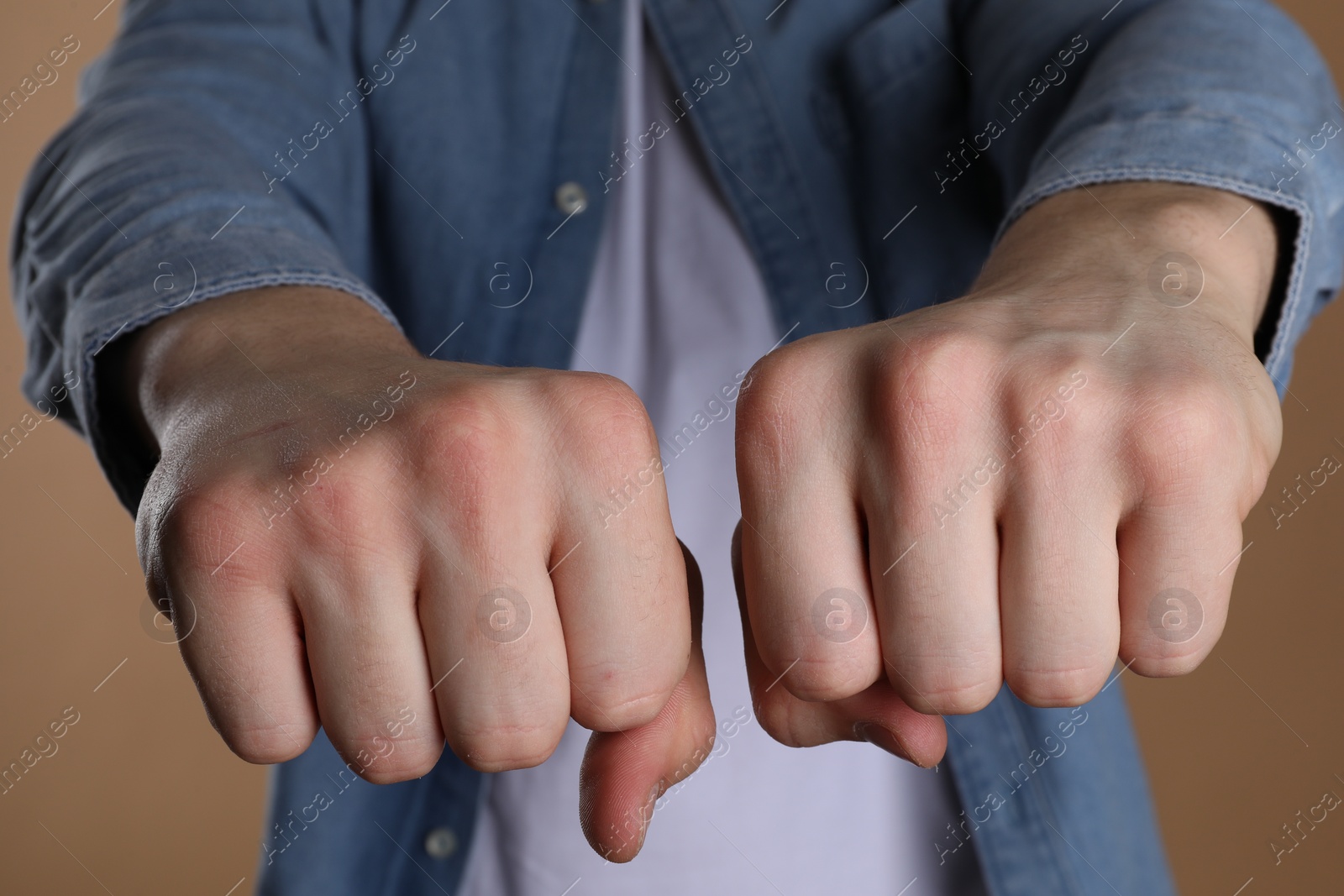 Photo of Man showing fists with space for tattoo on beige background, selective focus