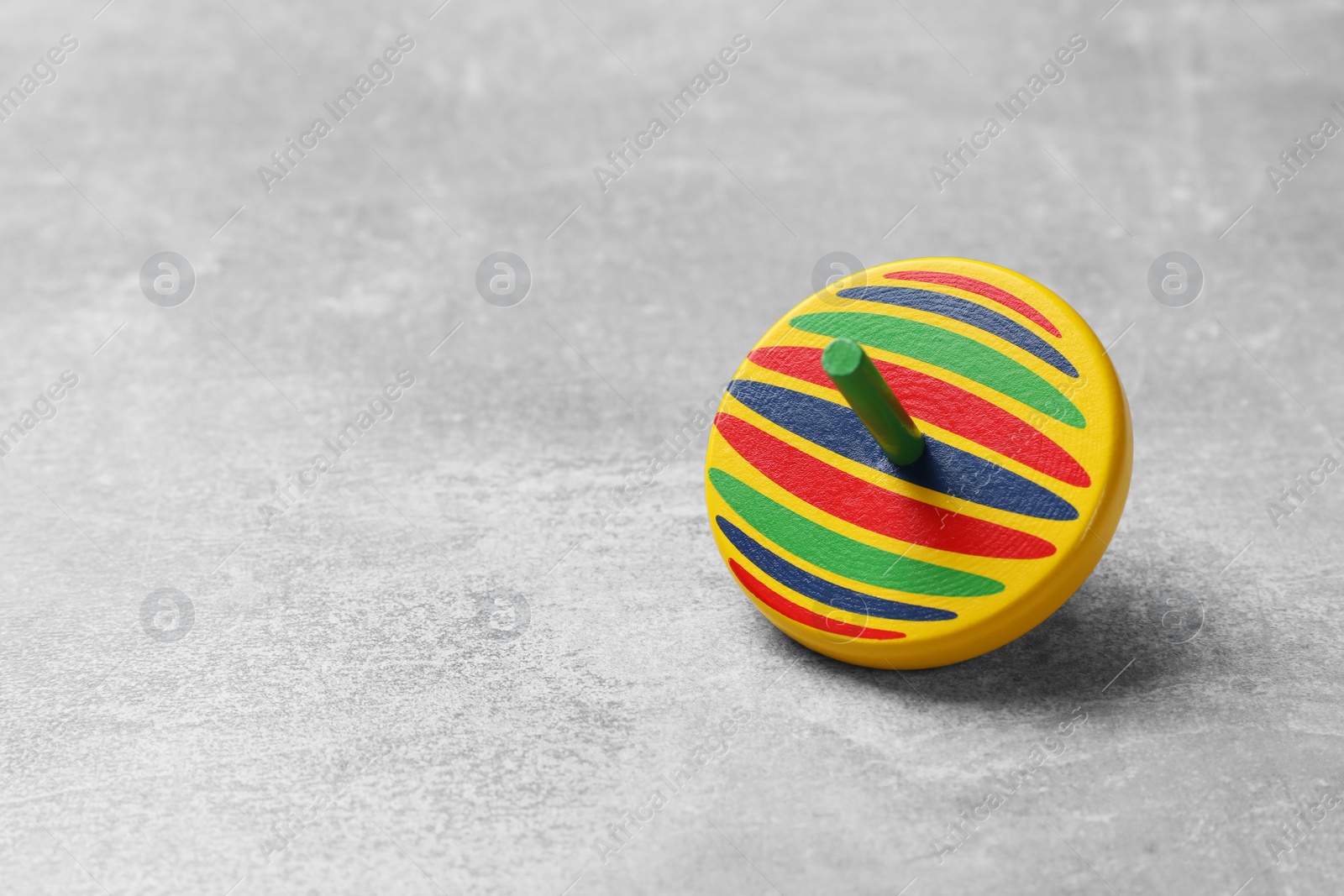 Photo of Bright spinning top on grey textured background, closeup. Space for text