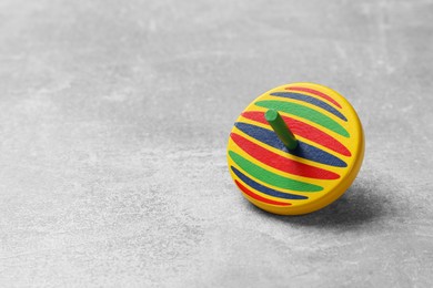 Photo of Bright spinning top on grey textured background, closeup. Space for text